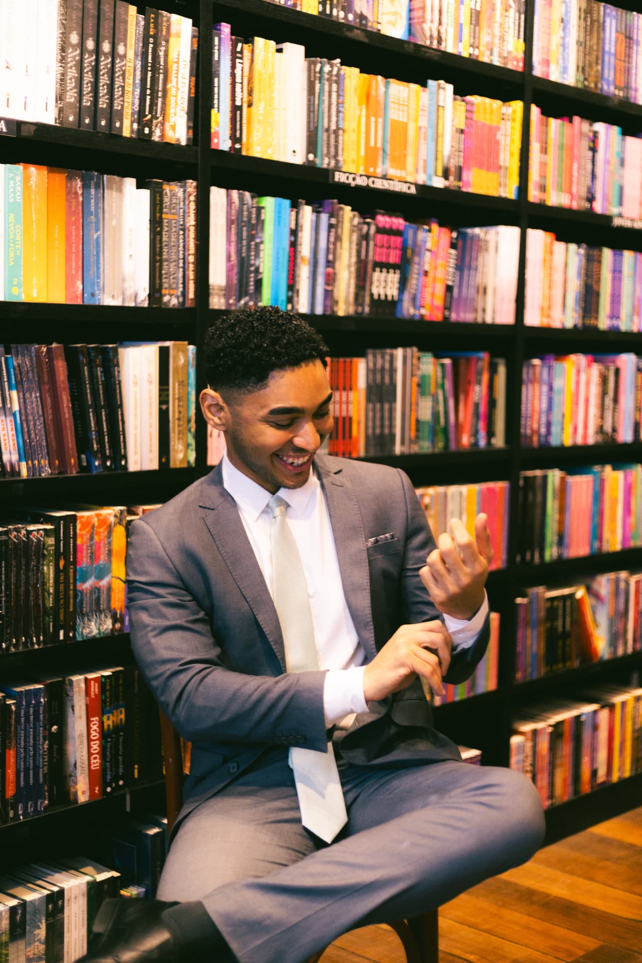 Advogado Douglas Aleixo sorrindo, sentado em frente a estantes de livros