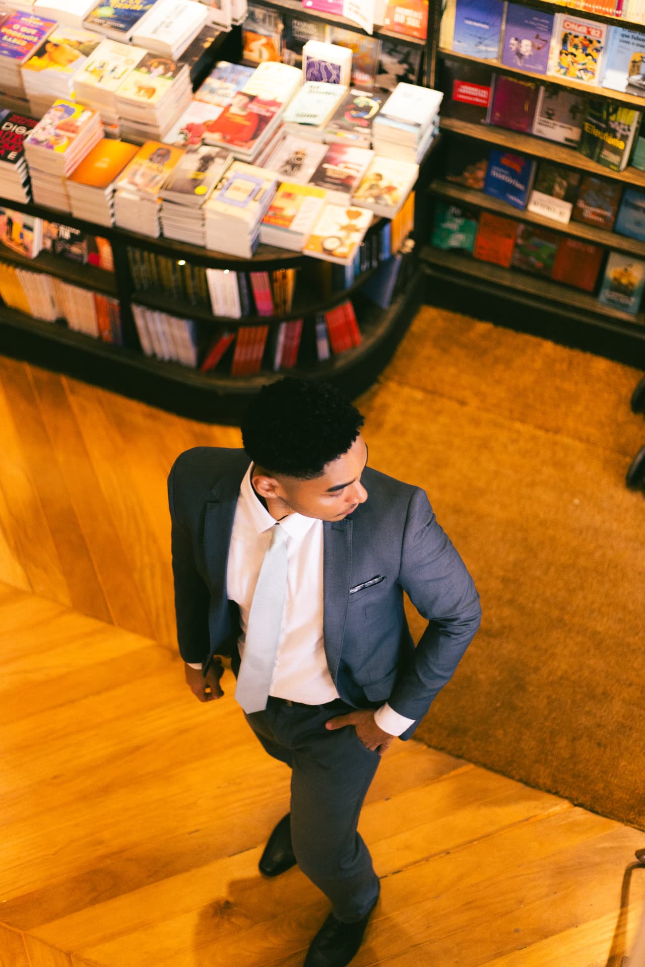 Advogado Douglas Aleixo de terno caminhando em uma livraria com piso de madeira